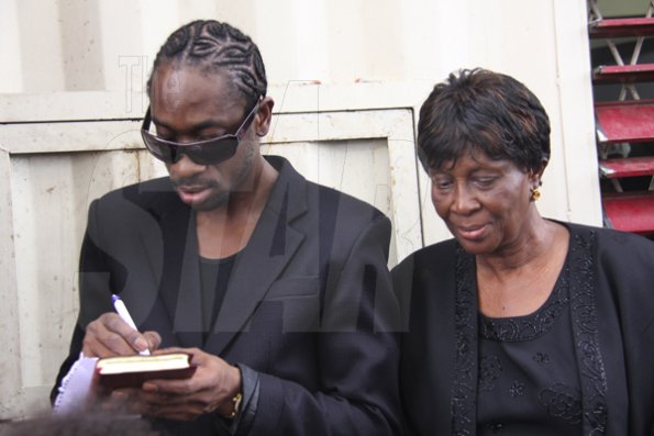 Anthony Minott/Freelance Photographer
Ivy Williams, (right), mother of DJ Bounty Killer, aka Rodney Price  pose beside her son, as he signs autograph after a church service on Sunday, April 18, 2010.