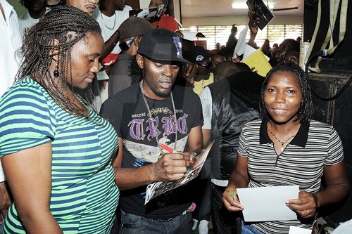 Ian Allen/Photographer
Bugle (centre) signs autographs for two framle fans at Champs 100 celebration at Calabar High School on Friday.