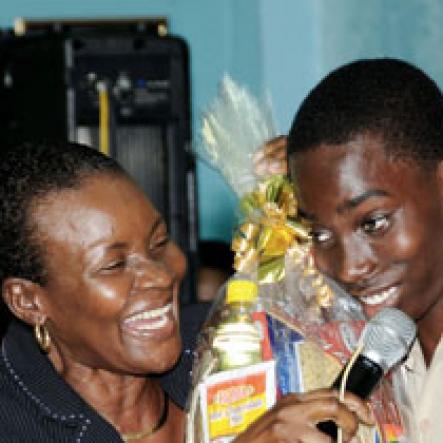 Ricardo Makyn/Staff Photographer.
GraceKennedy representative Mazie Miller (left) interacts with a young St Jago High student before presenting him with a gift basket during the Gleaner Champs 100 tour at the school yesterday.