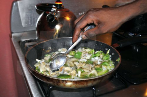 Gyptian prepares the saltfish last Wednesday at his home in Stony Hill.