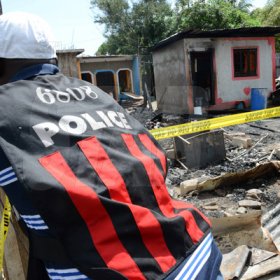 Rudolph Brown/Photographer
A police officer secure the crime scene after gunmen shoot up seven killing five including three children and set their home ablaze at Africa settlement in March Pen Community in Spanish Town on Sunday, October 9