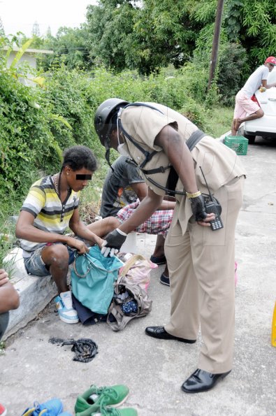 Gladstone Taylor / Photographer

A police officer looks into the bag of one of the men who was at the abandoned house on Millsborough Avenue in St Andrew yesterday. The police were at the property where they evicted a group of alleged homosexual men from the premises.