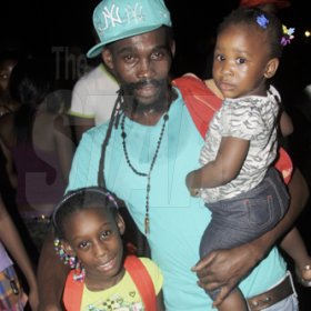 Anthony Minott/Freelance Photographer
Munga Honoureble with daughters,  Jahsenica Rhoden (left), and his  Thalia Rhoden during a Munga/Digicel back to school treat at Queens Borough, playfield, near Ackee W alk, in St Andrew recently.