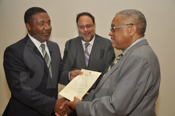 Jermaine Barnaby/Photographer
Phillip Paulwell (left) Minister of Science, Technology, Energy and Mining presents a legal document to UWI's pro vice chancellor and principal, Archibald McDonald (right) at the launch for the symbolic planting of the first legal Marijuana Plant at the Lecture Theatre Two (2) , Faculty of Medical Sciences Teaching and Research Complex on Monday April 20, 2015. Looking on is Minister of Justice Mark Golding.