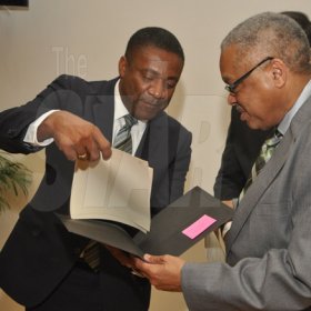 Jermaine Barnaby/Photographer
Phillip Paulwell (left) Minister of Science, Technology, Energy and Mining goes over some legal documents with UWI's pro vice chancellor and principal, Archibald McDonald (right) at the launch for the symbolic planting of the first legal Marijuana Plant at the Lecture Theatre Two (2) , Faculty of Medical Sciences Teaching and Research Complex on Monday April 20, 2015. Looking on is Minister of Justice Mark Golding partially hidden.